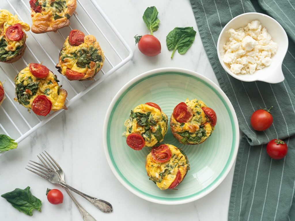 keto spinach feta egg muffins from Flavor Portal recipe on a plate with more on a rack