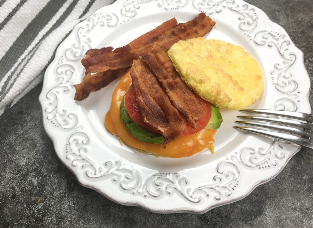 keto breakfast sandwich from Flavor Portal recipe open on a white plate with bacon strips