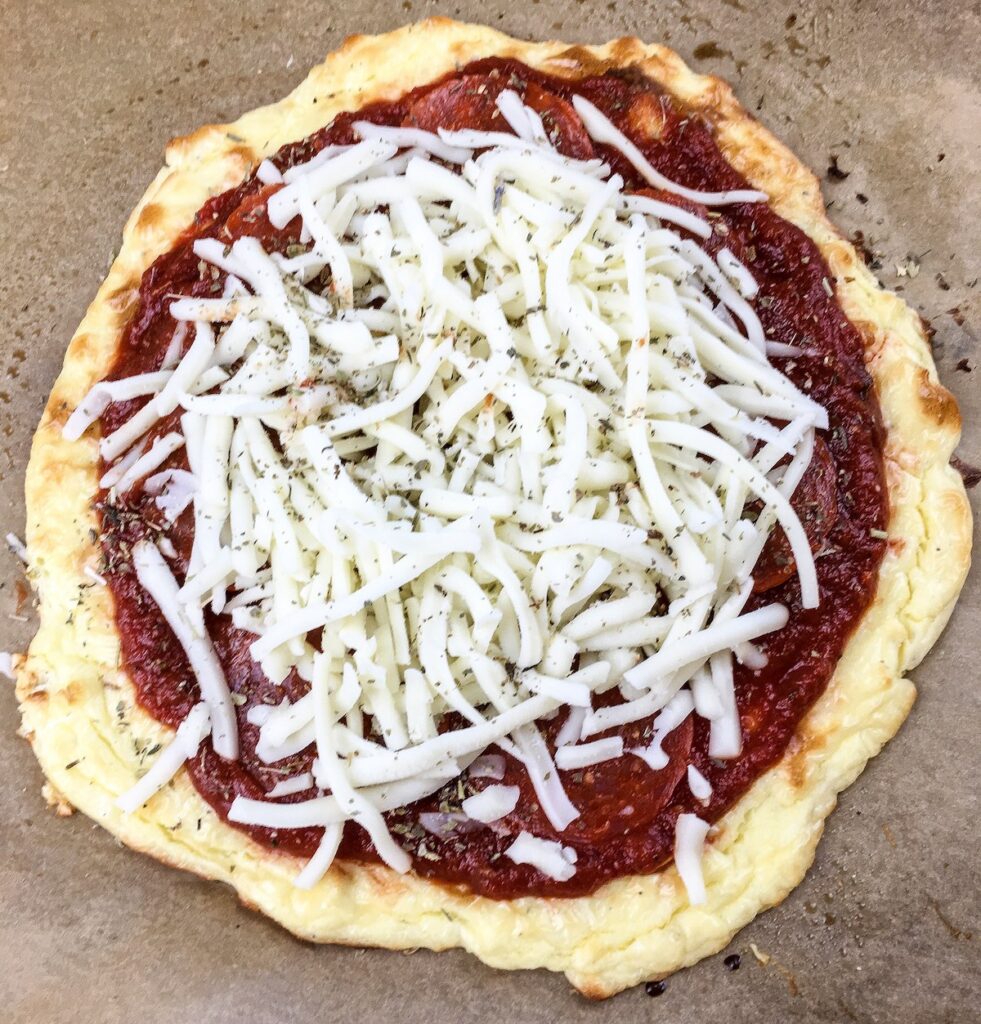 top view whole keto pizza with sauce and grated cheese from Flavor Portal recipe