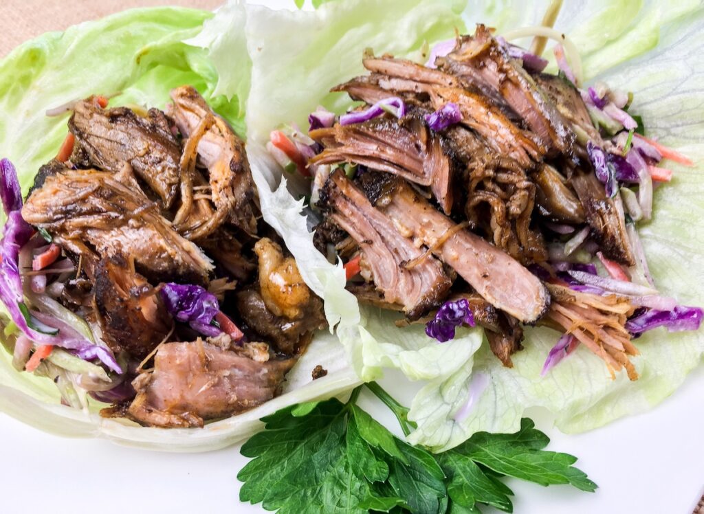 keto pulled pork from Flavor Portal recipe in lettuce wraps on a white plate garnished with parsley