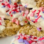 "Valentine rice krispie treats" text over a photo of white chocolate dipped half way and sprinkled