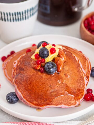 stack of spiced purple blueberry pancakes from Flavor Portal recipe topped with syrup, butter and fresh blueberries