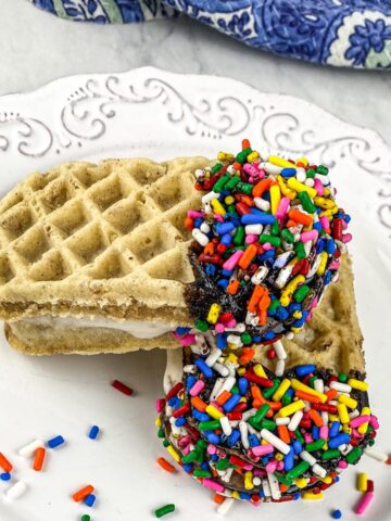 waffle ice cream sandwich dipped in chocolate syrup covered in rainbow sprinkles