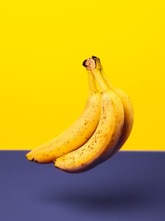 Bunch of overripe bananas in front of a yellow and blue background.